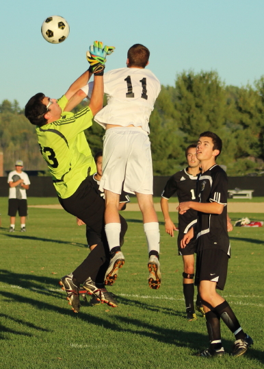 Eric Miller (#11) of Bridgton Academy contests a shot in front with Bowdoin GK Jake Muscato