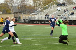 Jen Migliaccio pops the ball over the onrushing goalie Poli Tsiotos