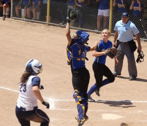 Catcher Hailey Perry jumps for a high throw as Cat Thompson nears the plate