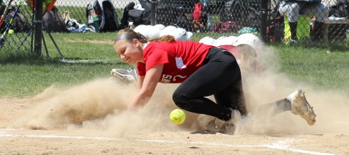 Amesbury pitcher Hayley Catania looks for the ball at home in a cloud of Jill Chelton dust