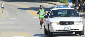 Moninda Marube follows the police car with Jim Johnson in the distance
